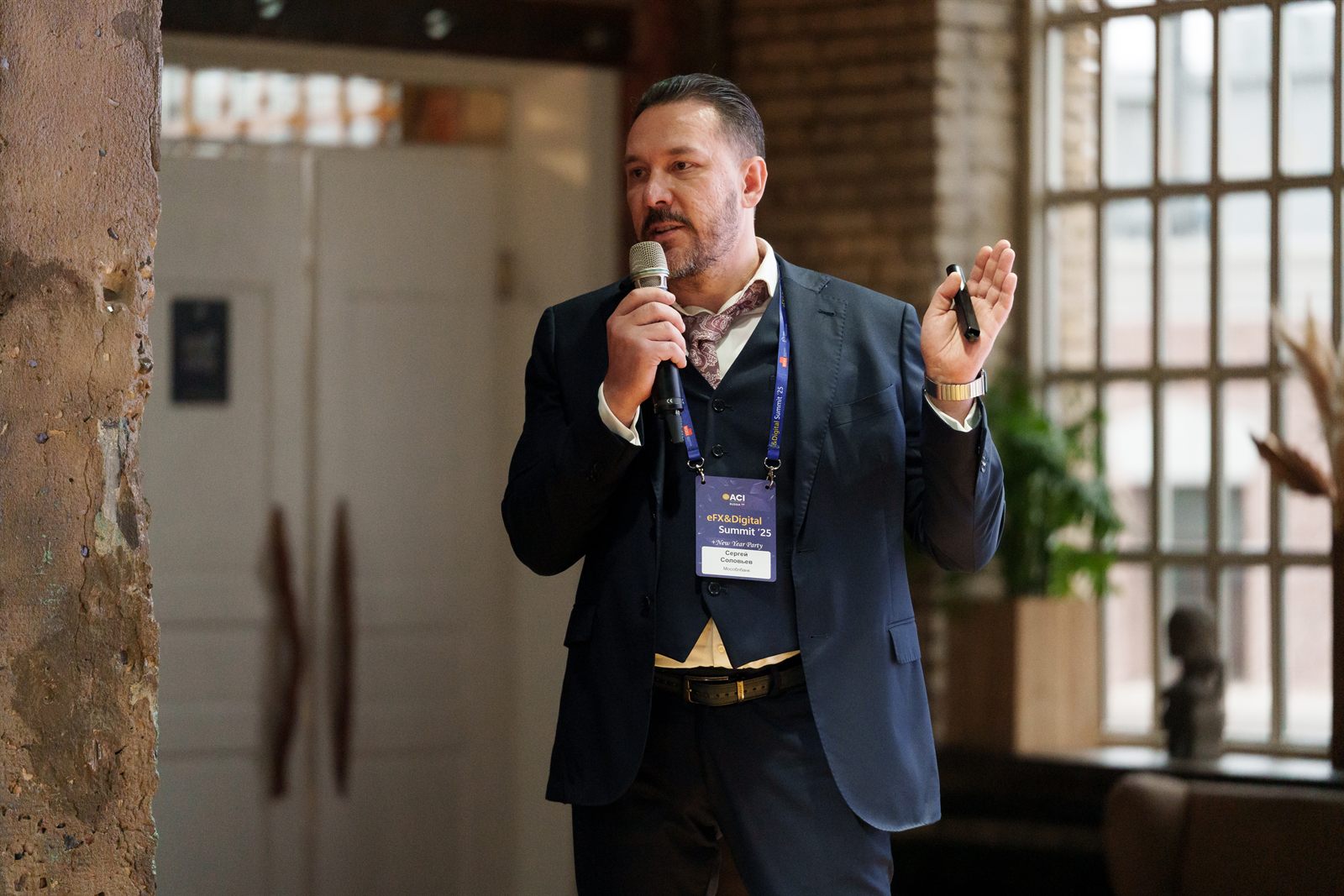 Sergei Solovev standing with a microphone and a presenter clicker, wearing an eFX and Digital Summit 2025 badge.